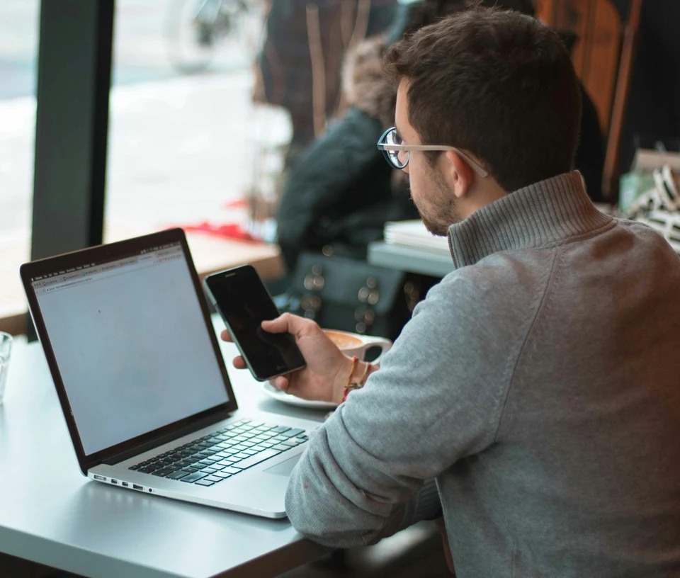 Laptop és telefon egy kávézó ablakánál, mögötte az utca.